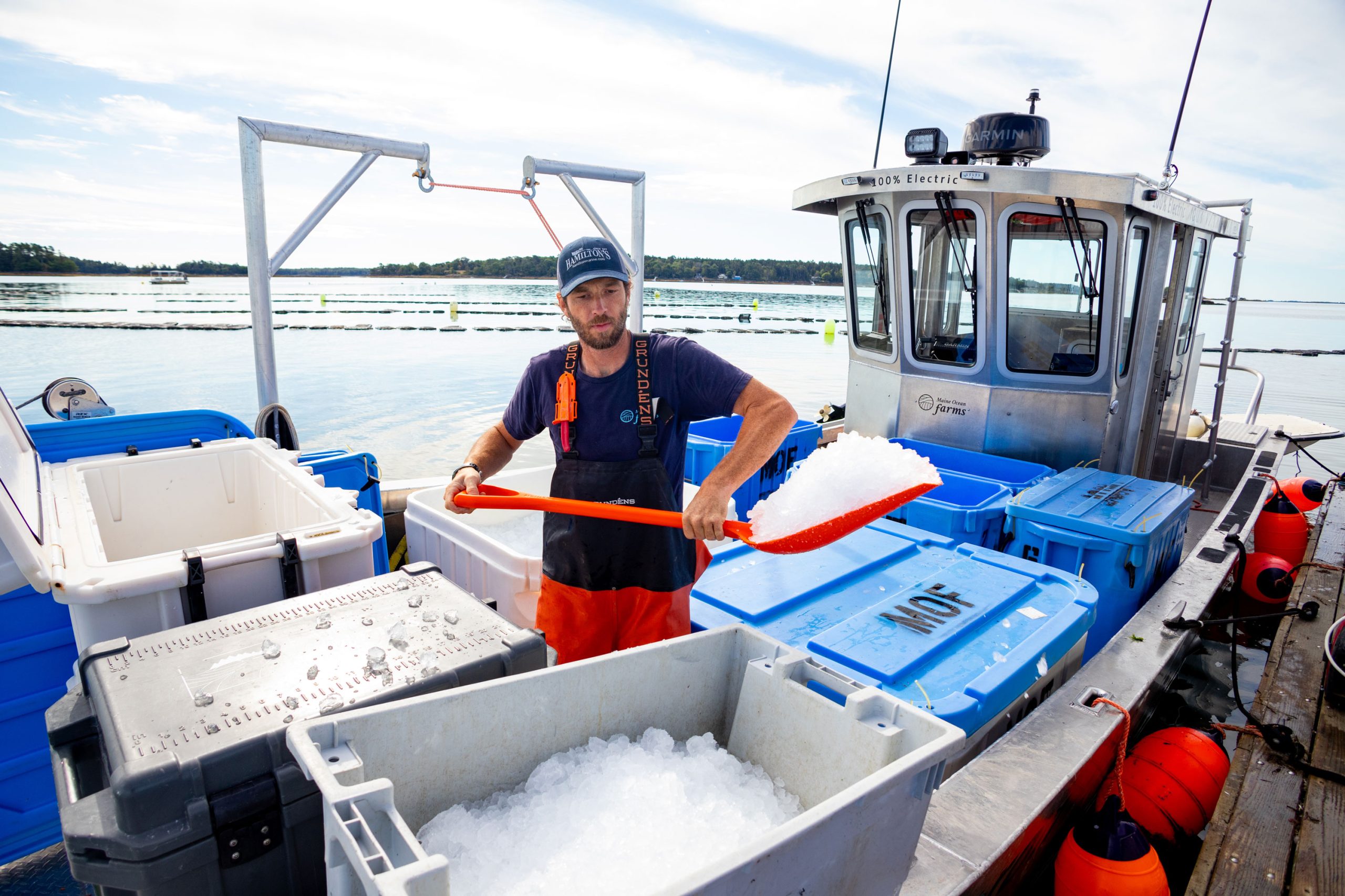Man aboard a boat shovels ice into a plastic container.